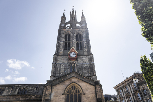 View of the historic St Nicholas Cathedral with its ornate clock face and stone tower rising against a clear blue sky in Newcastle upon Tyne England United Kingdom. View of the historic St Nicholas Cathedral with its ornate clock face and stone tower rising against a clear blue sky in Newcastle upon Tyne England United Kingdom.