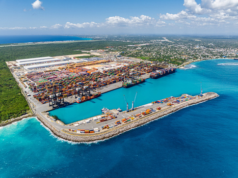 Aerial view of DP World Dominicana port facility with stacked shipping containers large cargo ships and cranes along the turquoise coastline in Boca Chica Santo Domingo Dominican Republic. Aerial view of DP World Dominicana port facility with stacked shipping containers large cargo ships and cranes along the turquoise coastline in Boca Chica Santo Domingo Dominican Republic.