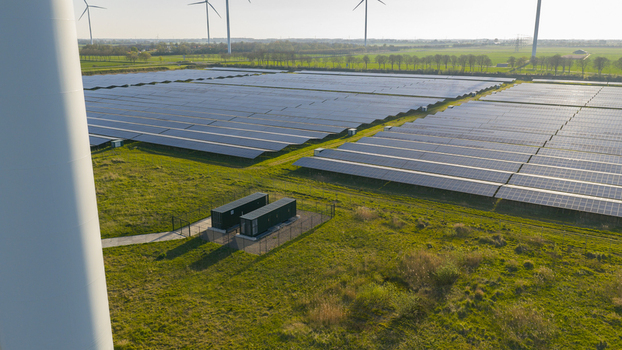 Aerial view of Solar park Delfzijl with rows of photovoltaic panels and wind turbines across green fields in Farmsum Groningen Netherlands. Aerial view of Solar park Delfzijl with rows of photovoltaic panels and wind turbines across green fields in Farmsum Groningen Netherlands.