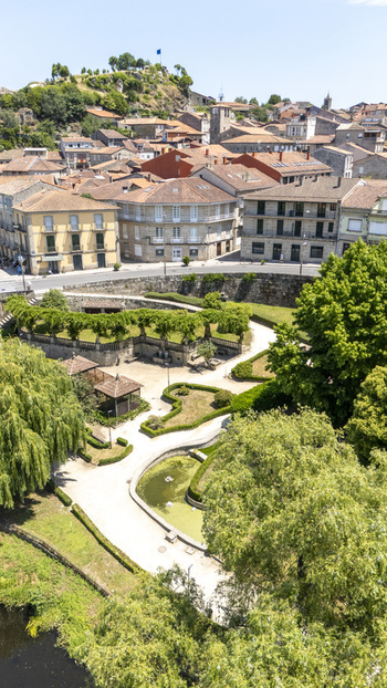 Aerial view of the historic town of Allariz featuring traditional stone buildings with terracotta rooftops a manicured park with a pond and lush greenery in Allariz Province of Ourense Spain. Aerial view of the historic town of Allariz featuring traditional stone buildings with terracotta rooftops a manicured park with a pond and lush greenery in Allariz Province of Ourense Spain.