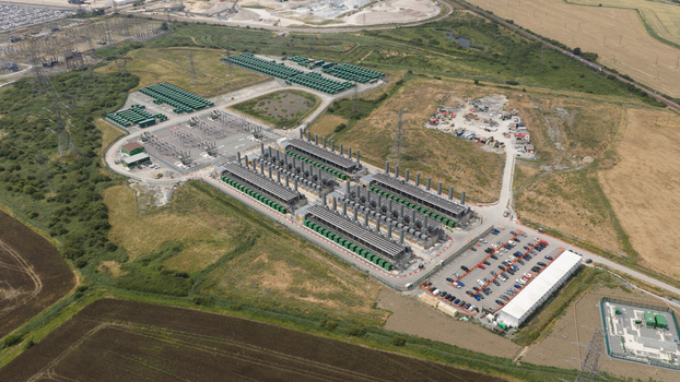 Aerial view of the Thurrock Flexible Generation Substation with rows of power generators green containers and a parking lot surrounded by fields Tilbury England United Kingdom.