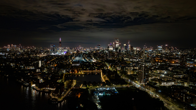 Aerial view of the London skyline at night featuring the illuminated Shard skyscraper dense urban lights and the River Thames in London England United Kingdom. Aerial view of the London skyline at night featuring the illuminated Shard skyscraper dense urban lights and the River Thames in London England United Kingdom.