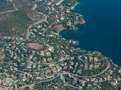 Aerial view of Le Trayas featuring Mediterranean villas with swimming pools among lush greenery and red rock cliffs along the coastline in Saint Raphael Provence Alpes Cote d Azur France. Aerial view of Le Trayas featuring Mediterranean villas with swimming pools among lush greenery and red rock cliffs along the coastline in Saint Raphael Provence Alpes Cote d Azur France.