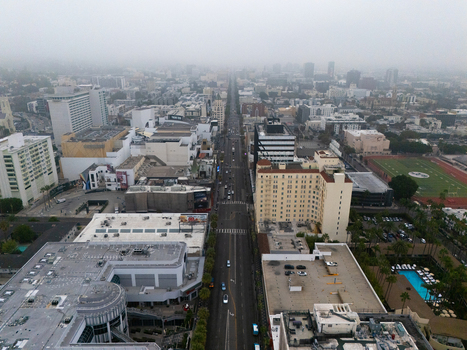 Aerial view of Hollywood Boulevard and the Hollywood Walk of Fame featuring urban buildings palm trees and city streets under a hazy sky in Los Angeles California United States.
