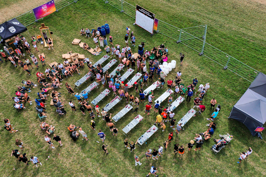 Herzogenaurach Germany 26 July 2025 Aerial view of people gathered around long tables at the Open Beatz Festival on a grassy field with tents and fences.
