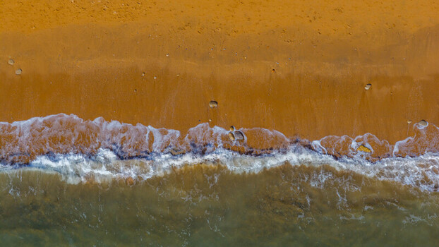 Aerial view of the golden sandy beach and waves crashing on the shore at West Bay England United Kingdom. Aerial view of the golden sandy beach and waves crashing on the shore at West Bay England United Kingdom.