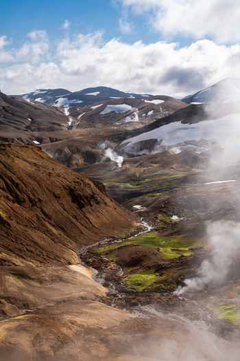 View of a rugged landscape where steam rises amidst the stark terrain hinting at geothermal activity beneath the surface Hrunamannahreppur Iceland.