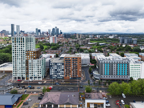 Aerial view of MediaCityUK with modern apartment buildings urban streets and the Manchester skyline in the distance in Salford England United Kingdom. Aerial view of MediaCityUK with modern apartment buildings urban streets and the Manchester skyline in the distance in Salford England United Kingdom.