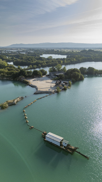 Aerial view of the Extraccion de aridos Lima SL sand extraction facility with floating equipment on a turquoise lake surrounded by greenery in Vilarino das Poldras Ourense Spain. Aerial view of the Extraccion de aridos Lima SL sand extraction facility with floating equipment on a turquoise lake surrounded by greenery in Vilarino das Poldras Ourense Spain.