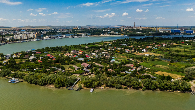 Aerial view of the Danube river and the town of Tulcea with lush green vegetation residential houses and boats along the riverbank in Tulcea Tulcea Romania.