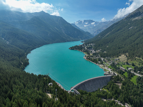 Aerial view of the turquoise Lago di Ceresole and its dam surrounded by dense pine forests and majestic alpine peaks in Ceresole Reale Piedmont Italy. Aerial view of the turquoise Lago di Ceresole and its dam surrounded by dense pine forests and majestic alpine peaks in Ceresole Reale Piedmont Italy.