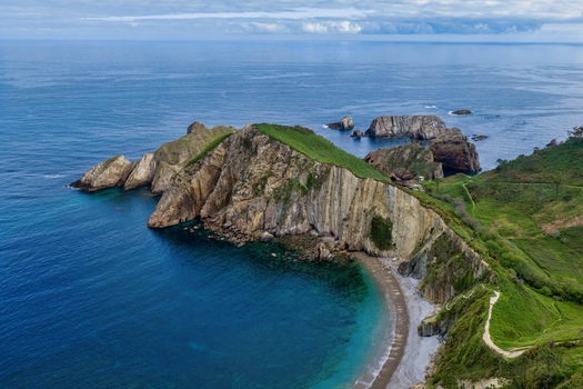 Aerial view of Silence Beach Viewpoint featuring dramatic cliffs and turquoise waters along the rugged coastline in Cudillero Asturias Spain.