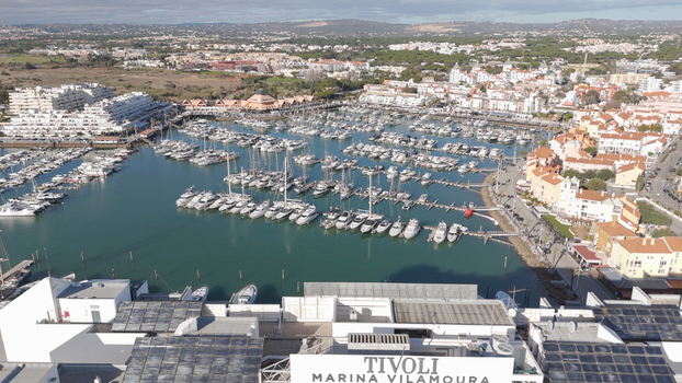 Aerial view of Vilamoura Marina filled with numerous yachts and boats surrounded by white buildings and urban infrastructure in Quarteira Faro District Portugal.