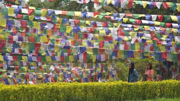 View of colorful prayer flags and tourists in Lumbini Nepal.
