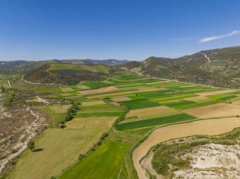 Aerial view of the Vjosa Wild River National Park featuring a patchwork of agricultural fields rolling hills and rural landscape in Permet Gjirokaster County Albania. Aerial view of the Vjosa Wild River National Park featuring a patchwork of agricultural fields rolling hills and rural landscape in Permet Gjirokaster County Albania.