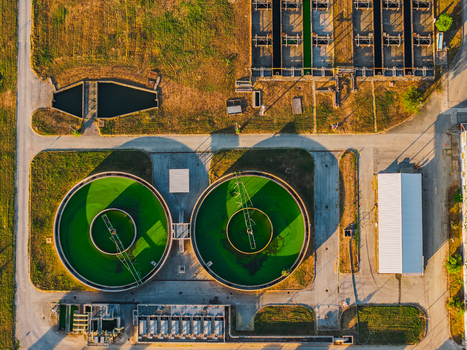Aerial view of a water treatment plant with circular sedimentation tanks and industrial infrastructure in Rome Lazio Italy.