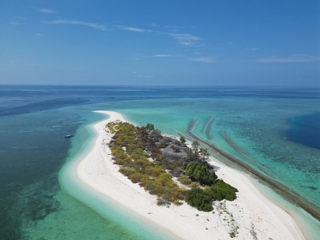 Aerial view of Pulau Ndaa a small tropical island with white sand beaches lush vegetation and turquoise coral reef waters in Tomia South East Sulawesi Indonesia.
