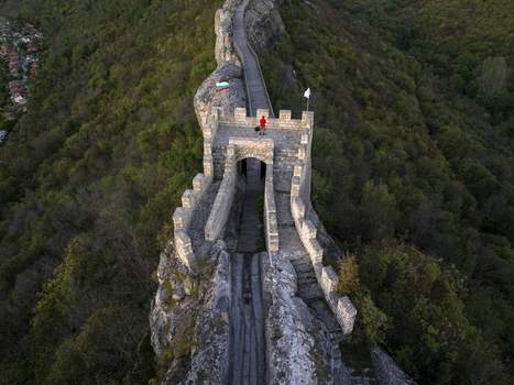 Aerial view of Ovech Fortress with its stone walls wooden walkway and a person in a red jacket standing on the ramparts surrounded by lush forests in Provadia Varna Bulgaria. Aerial view of Ovech Fortress with its stone walls wooden walkway and a person in a red jacket standing on the ramparts surrounded by lush forests in Provadia Varna Bulgaria.