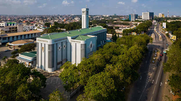 Aerial view of the Holy Spirit Cathedral with its distinctive green roof and tower surrounded by lush trees and urban infrastructure in Accra Greater Accra Region Ghana. Aerial view of the Holy Spirit Cathedral with its distinctive green roof and tower surrounded by lush trees and urban infrastructure in Accra Greater Accra Region Ghana.