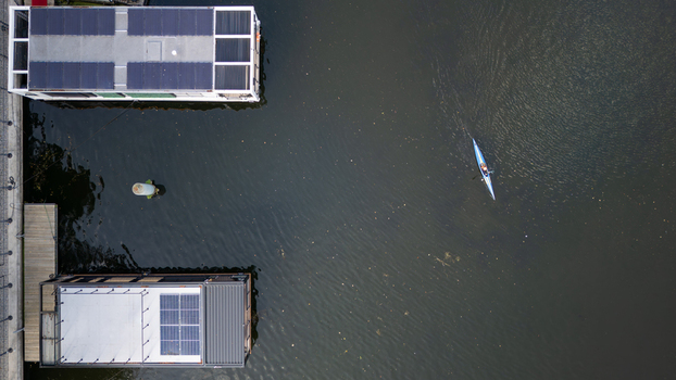 Aerial view of placid waters reflecting the sky with houseboats lining the shore and a lone kayaker gliding through the river Bydgoszcz Województwo kujawsko pomorskie Poland. Aerial view of placid waters reflecting the sky with houseboats lining the shore and a lone kayaker gliding through the river Bydgoszcz Województwo kujawsko pomorskie Poland.