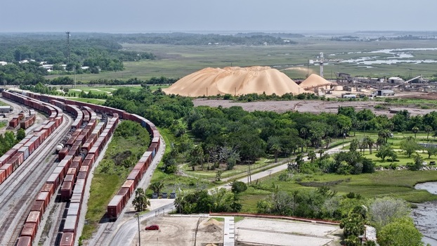 Aerial view of a massive sand dune contrasting sharply with the dark green trees and industrial structures a testament to human impact Fernandina Beach Florida United States. Aerial view of a massive sand dune contrasting sharply with the dark green trees and industrial structures a testament to human impact Fernandina Beach Florida United States.