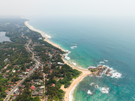 Aerial view of the tropical coastline with sandy beaches turquoise ocean waves and lush green vegetation in Dodanduwa Southern Province Sri Lanka. Aerial view of the tropical coastline with sandy beaches turquoise ocean waves and lush green vegetation in Dodanduwa Southern Province Sri Lanka.