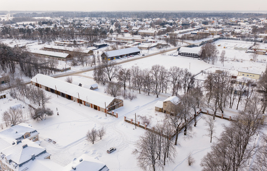 Aerial view of long buildings and snow covered houses surrounded by bare trees in a winter landscape Lithuania. Aerial view of long buildings and snow covered houses surrounded by bare trees in a winter landscape Lithuania.