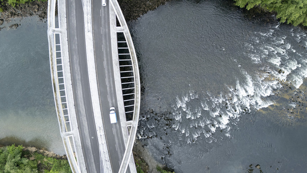 Aerial view of the modern Ponte do Milenio bridge with a white van driving over the flowing river and rapids in Orense Ourense Spain. Aerial view of the modern Ponte do Milenio bridge with a white van driving over the flowing river and rapids in Orense Ourense Spain.