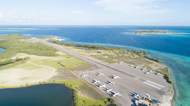 Aerial view of Los Roques archipelago airport with small aircraft on the tarmac surrounded by turquoise sea and vegetation in Los Roques Dependencias Federales Venezuela. Aerial view of Los Roques archipelago airport with small aircraft on the tarmac surrounded by turquoise sea and vegetation in Los Roques Dependencias Federales Venezuela.