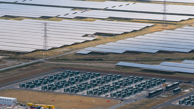 Aerial view of a large solar farm featuring extensive rows of photovoltaic panels and a battery energy storage system with green containers in London England United Kingdom.