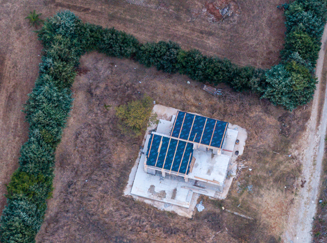 Aerial view of a house under construction with a dark roof surrounded by dry fields and a dense hedge in San Vito Lo Capo Sicilia Italy. Aerial view of a house under construction with a dark roof surrounded by dry fields and a dense hedge in San Vito Lo Capo Sicilia Italy.