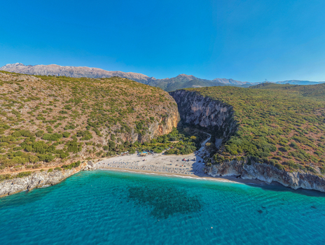 Aerial view of Gjipe Beach featuring a secluded sandy cove nestled between towering limestone cliffs and turquoise Ionian Sea waters in Vlore County Albania. Aerial view of Gjipe Beach featuring a secluded sandy cove nestled between towering limestone cliffs and turquoise Ionian Sea waters in Vlore County Albania.
