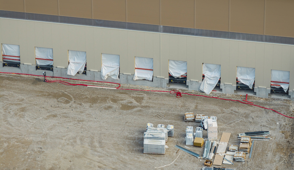 Aerial view of a modern logistics warehouse with multiple loading docks and construction materials on the ground in Loriol sur Drome Auvergne Rhone Alpes France.