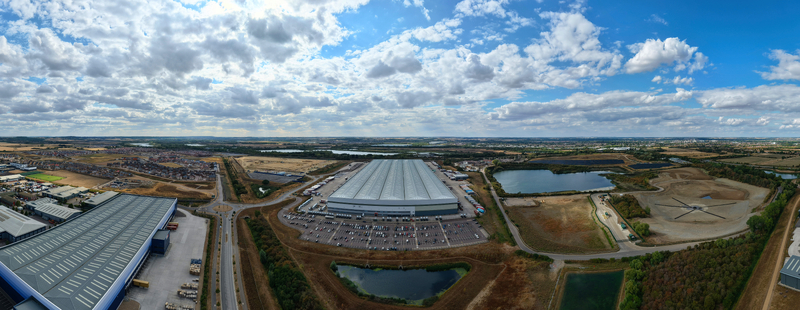 Aerial view of a large logistics hub with industrial warehouses parked HGVs and surrounding ponds under a cloudy blue sky in Bedford England United Kingdom. Aerial view of a large logistics hub with industrial warehouses parked HGVs and surrounding ponds under a cloudy blue sky in Bedford England United Kingdom.