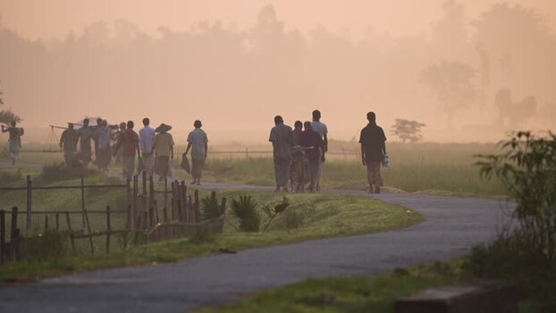 View of people walking on a misty rural road in Bogura Bangladesh.