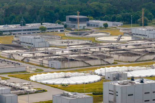 Aerial view of the wastewater treatment plant with circular sedimentation tanks industrial buildings and surrounding green areas in Warsaw Masovian Voivodeship Poland. Aerial view of the wastewater treatment plant with circular sedimentation tanks industrial buildings and surrounding green areas in Warsaw Masovian Voivodeship Poland.
