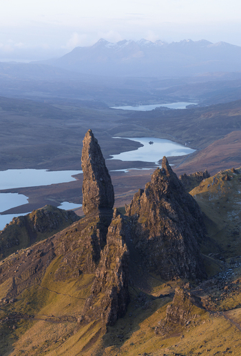 Aerial view of The Storr rock formation with jagged pinnacles overlooking rolling hills and distant lochs under soft morning light Isle of Skye Scotland United Kingdom. Aerial view of The Storr rock formation with jagged pinnacles overlooking rolling hills and distant lochs under soft morning light Isle of Skye Scotland United Kingdom.