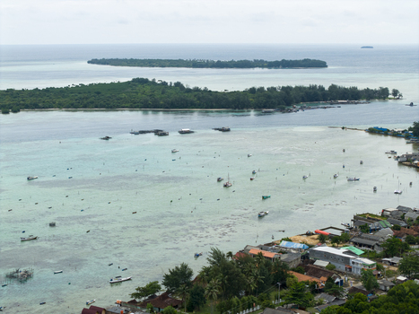 Aerial view of boats dot the turquoise waters near the shore contrasting with the lush green islands in the distance Karimunjawa Central Java Indonesia. Aerial view of boats dot the turquoise waters near the shore contrasting with the lush green islands in the distance Karimunjawa Central Java Indonesia.