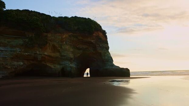 View of a person in a cave archway on the beach New Zealand. View of a person in a cave archway on the beach New Zealand.