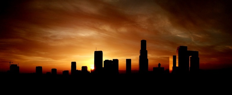 Aerial view of the Los Angeles skyline silhouetted against a vibrant sunset sky with glowing orange clouds over the city buildings in Los Angeles California United States.
