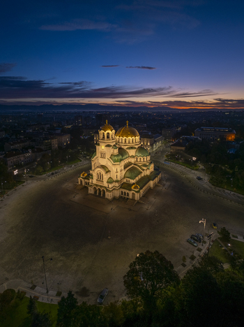 Aerial view of the illuminated Patriarchal Cathedral St. Alexander Nevsky at dusk surrounded by the city square and urban landscape in Sofia Sofia City Province Bulgaria. Aerial view of the illuminated Patriarchal Cathedral St. Alexander Nevsky at dusk surrounded by the city square and urban landscape in Sofia Sofia City Province Bulgaria.