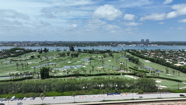 Aerial view of the lush green golf course contrasting against the blue waters with buildings in the distance Palm Beach Florida United States.