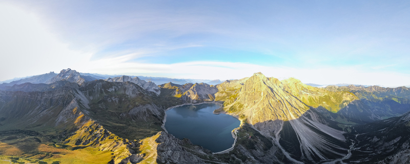 Aerial view of the turquoise waters of Lunersee surrounded by rugged alpine peaks steep rocky slopes and lush mountain meadows in Vandans Vorarlberg Austria. Aerial view of the turquoise waters of Lunersee surrounded by rugged alpine peaks steep rocky slopes and lush mountain meadows in Vandans Vorarlberg Austria.