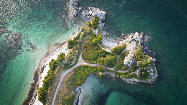 Aerial view of a small rugged island with vibrant green vegetation contrasting against the turquoise waters paths winding through the landscape Roscoff Finistere France.