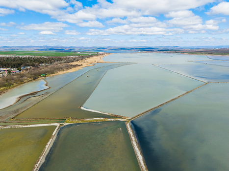 Aerial view of Lake Atanasovsko showing geometric salt evaporation ponds and narrow dikes under a blue sky with clouds in Burgas Burgas Bulgaria. Aerial view of Lake Atanasovsko showing geometric salt evaporation ponds and narrow dikes under a blue sky with clouds in Burgas Burgas Bulgaria.
