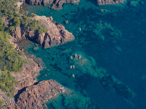 Aerial view of Le Trayas coastline with kayakers paddling in the clear turquoise waters along the red rocky cliffs of Saint Raphael Provence Alpes Cote d Azur France. Aerial view of Le Trayas coastline with kayakers paddling in the clear turquoise waters along the red rocky cliffs of Saint Raphael Provence Alpes Cote d Azur France.
