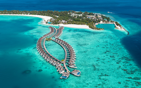 Aerial view of luxury resort overwater bungalows arranged in a fish shape over a turquoise lagoon surrounded by white sand beaches in Kudahuvadhoo Dhaalu Atoll Maldives. Aerial view of luxury resort overwater bungalows arranged in a fish shape over a turquoise lagoon surrounded by white sand beaches in Kudahuvadhoo Dhaalu Atoll Maldives.