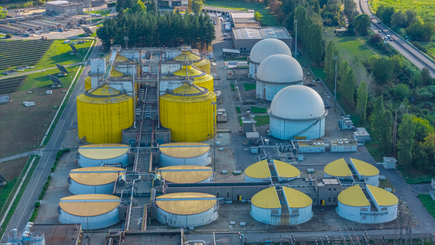 Aerial view of anaerobic digesters biogas storage domes and wastewater processing tanks at a large environmental facility in Italy.