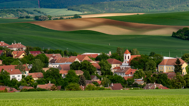 View of a small village with red tiled roofs and a church tower nestled among rolling green hills in the Moravian countryside Brno City District South Moravian Region Czechia.