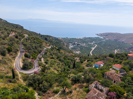 Aerial view of a winding mountain road descending through lush olive groves toward the coastal village and the blue sea in Qeparo Fshat Vlore County Albania. Aerial view of a winding mountain road descending through lush olive groves toward the coastal village and the blue sea in Qeparo Fshat Vlore County Albania.